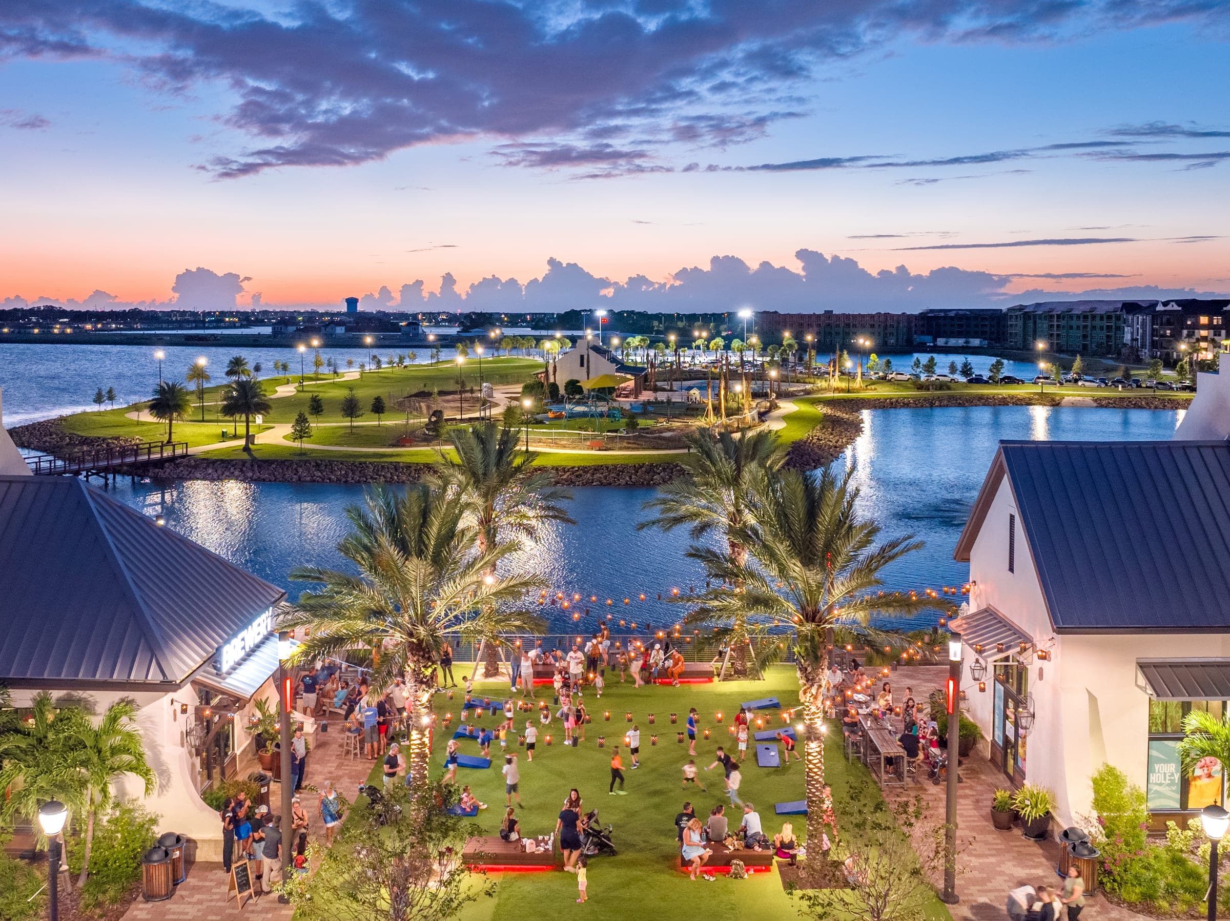 Waterside Place at Lakewood Ranch at dusk, lakefront brewery patio, string lights, and lawn games